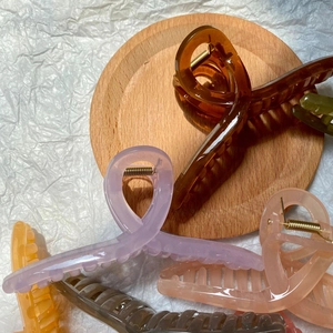 Detailed view of large jelly-colored hair claws with strong metal springs on a wooden tray