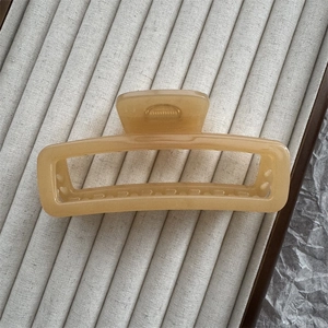 Macro view of rectangular marble-textured acetate hair claw clip in creamy yellow