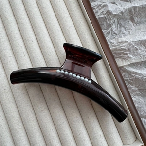Detail of tortoise shell claw clip with pearls on a soft velvet jewelry tray