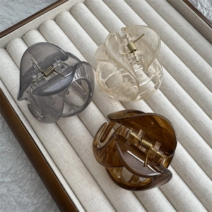 Trois pinces à cheveux en résine translucide grise, crème et ambre sur un plateau à bijoux