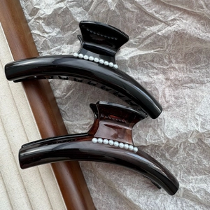 Detail view of two large French pearl hair claws in sleek black and tortoise shell resin