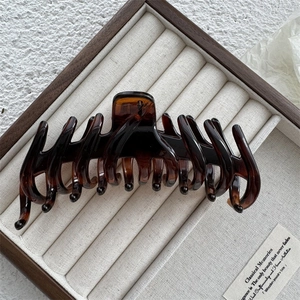 Detail of a large dark brown tortoiseshell hair claw clip in a wooden jewelry box