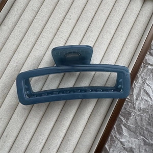 Detail of dark blue-grey rectangular hair claw clip with glossy resin finish on display