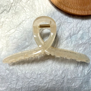 Detail of translucent cream white large hair claw clip with golden metal spring