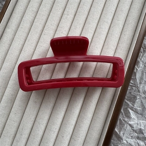 Detail of dark red rectangular hair claw clip on beige velvet display tray