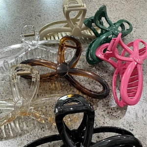 Detail view of large butterfly bow hair claws in six various colors on stone texture