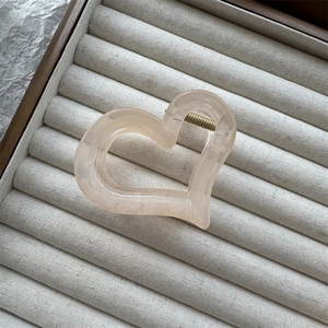 Dettaglio molletta per capelli a forma di cuore rosa opaco con meccanismo a molla in metallo
