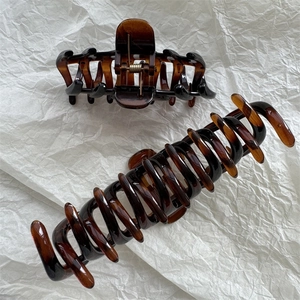 Detail of large amber hair claws with tortoiseshell pattern on white textured paper