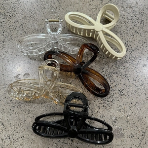 Fashionable hollow bow-shaped claw clips in five stylish colors on a stone surface