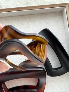 Detail of elegant amber and matte black shark hair clips on a wooden display tray