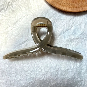 Top view of a large dark grey semi-transparent jelly claw clip on white crinkled paper