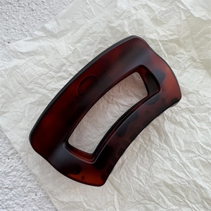Detail of tortoise shell rectangular hair claw clip with amber brown resin texture