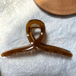 Detail view of amber translucent hair claw clip with glossy finish and sturdy metal spring