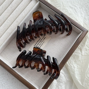 Detailed view of large tortoiseshell claw clips with amber texture on a wooden jewelry tray