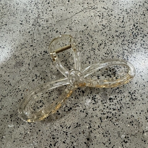 Detail shot of a large bow hair claw clip with gold foil flakes inside clear resin