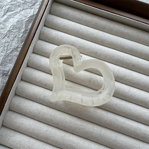 Dettaglio molletta per capelli a forma di cuore color crema su vassoio gioielli