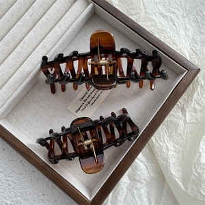 Detailed close-up of large amber tortoiseshell hair claws with strong gold metal springs