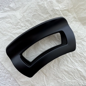 Close-up of large matte black rectangle claw clip with hollow curved design for thick hair