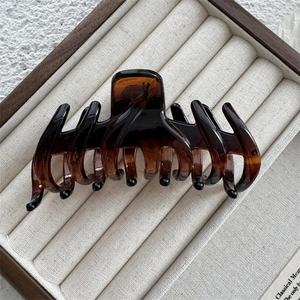 Close-up of large amber tortoiseshell hair claw clip with glossy finish in a gift box