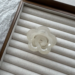 Dettaglio di un fermaglio per capelli a fiore bianco crema su vassoio in legno elegante