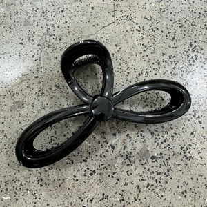 Macro shot of large black glossy hollow hair claw clip with metallic spring mechanism