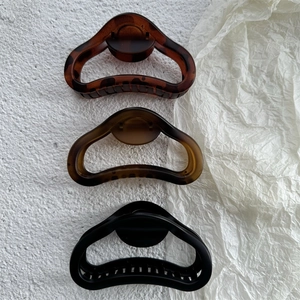 Detail view of large matte hollow shark hair claws in tortoise shell and amber resin