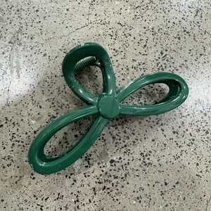 Detailed view of large dark green flower hair claw clip with glossy finish and metal spring
