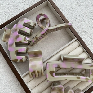 Gros plan de pinces à cheveux à motif léopard dans une boîte à bijoux aux tons gris-rose