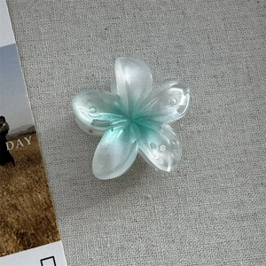 Détail macro de la pince à cheveux fleur de frangipanier avec dégradé nacré et fini mat