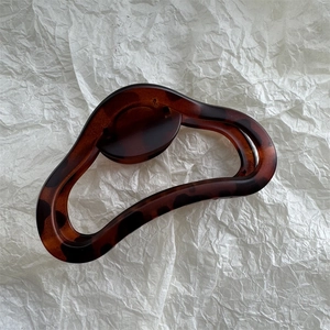 Detail view of large amber tortoiseshell hair claw clip with elegant hollowed-out design