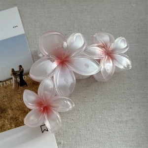 Détail de la pince à cheveux en forme de fleur de frangipanier rose et blanc nacré