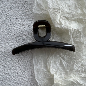 Detailed view of glossy dark brown jelly hair claw clip with elegant curved design