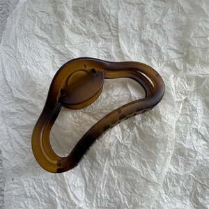 Detail showing the matte amber hair claw clip with its unique wavy resin texture design