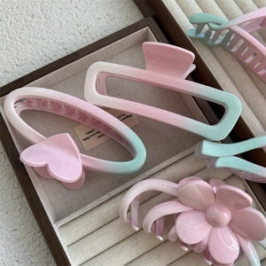 Detailed view of pink and green gradient hair claws in heart and flower shapes