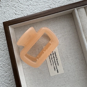 Vue détaillée d'une pince à cheveux orange géométrique dans une boîte en bois rustique
