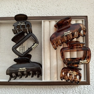 Detailed view of vintage amber and tortoise shell hair claws on a velvet display tray