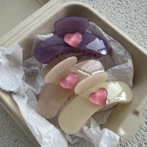 Close-up of three jelly heart hair claws in purple, pink and yellow within a gift box