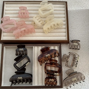 Close-up of 12 elegant square hair claws in various colors on a wooden tray