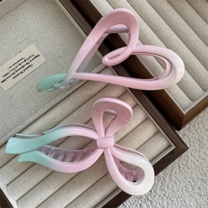 Pink and green gradient hair clips in heart and bow shapes on a velvet tray
