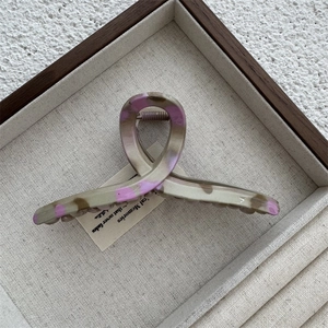 Détail d'une grande pince à cheveux marbrée grise et violette posée sur un plateau