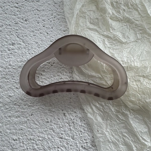 Dettaglio della consistenza opaca e del design ergonomico della clip per capelli satinata