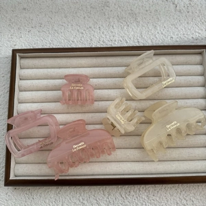 Close-up of minimalist matte hair claws in pink and cream on a wooden jewelry display