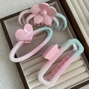 Pink and green gradient hair claw clip set with flower and heart shapes in a display box