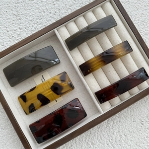 Detail view of five assorted acetate hair clips in a beige jewelry display box