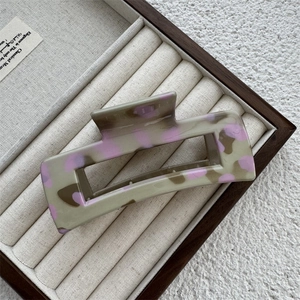 Détail d'une pince à cheveux en acétate gris et rose dans un coffret de présentation