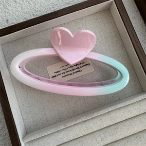 Detail of large heart hair claw clip with pink and green gradient in a jewelry box