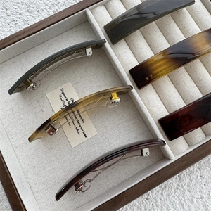 Close-up of vintage resin hair clips in amber and emerald tones on a wooden tray