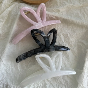 Macro view of three large marble pattern butterfly hair claws in pink, grey and white