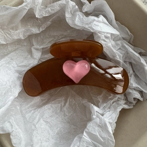 Detailed close-up of amber resin hair claw clip with a pink heart on white paper