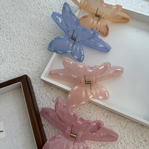 Detailed view of butterfly claw clips with ribbon woven edges in four soft pastel colors